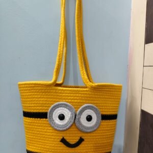 Handcrafted yellow cotton rope tote bag with cartoon-inspired face design, dual shoulder handles, and spacious interior for women.