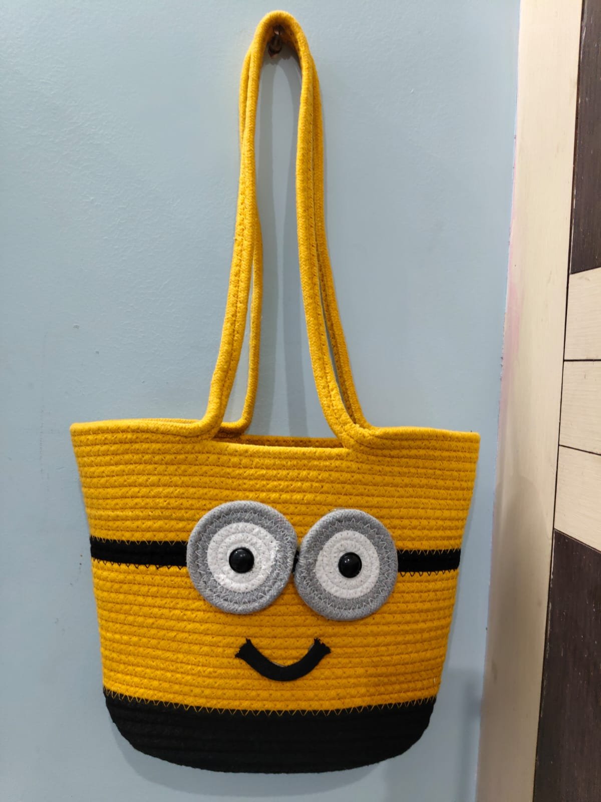 Handcrafted yellow cotton rope tote bag with cartoon-inspired face design, dual shoulder handles, and spacious interior for women.